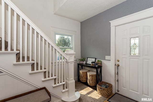 carpeted foyer entrance featuring a textured ceiling