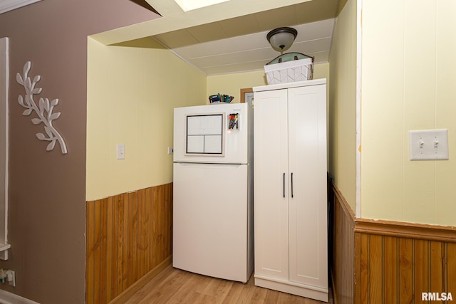 interior space with wood walls, white fridge, and light hardwood / wood-style flooring