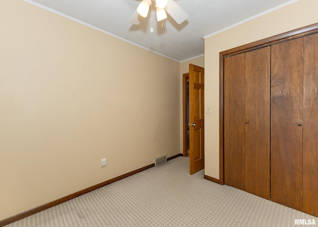 unfurnished bedroom featuring light carpet, a closet, ornamental molding, and ceiling fan