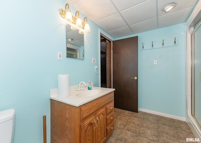 bathroom featuring a paneled ceiling, vanity, toilet, and walk in shower