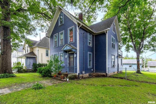 view of front of home with a chimney, fence, and a front lawn