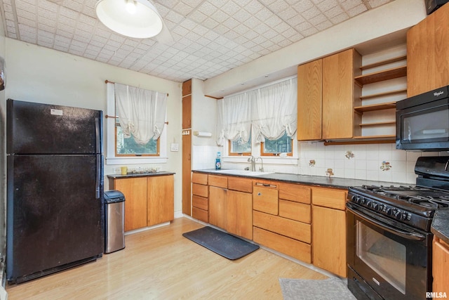 kitchen with sink, tasteful backsplash, light hardwood / wood-style flooring, and black appliances