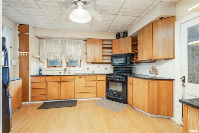 kitchen with tasteful backsplash, ceiling fan, sink, black appliances, and light hardwood / wood-style flooring