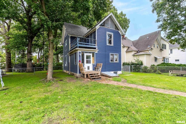 rear view of property with a balcony and a lawn