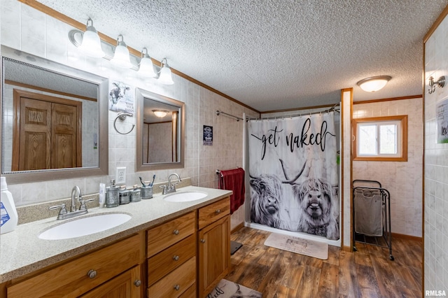 bathroom featuring vanity, a textured ceiling, crown molding, hardwood / wood-style flooring, and tile walls