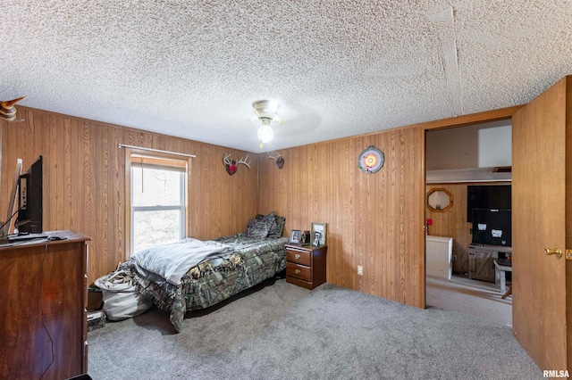 carpeted bedroom with a textured ceiling, ceiling fan, and wooden walls