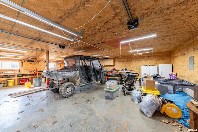 garage with a workshop area, electric panel, and a garage door opener