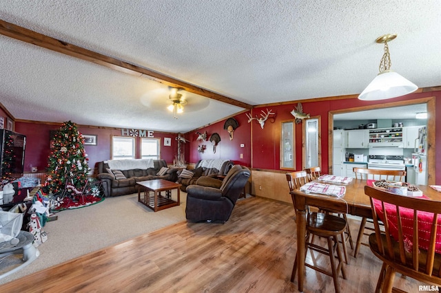 living room with ceiling fan, vaulted ceiling with beams, crown molding, a textured ceiling, and hardwood / wood-style flooring