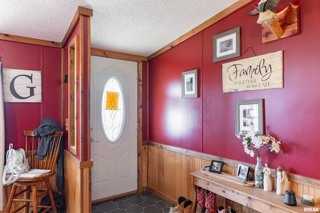 entryway with lofted ceiling, a textured ceiling, and wooden walls