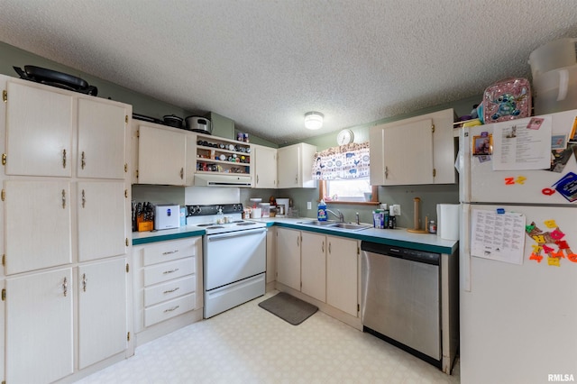 kitchen with white appliances, cream cabinets, sink, vaulted ceiling, and a textured ceiling