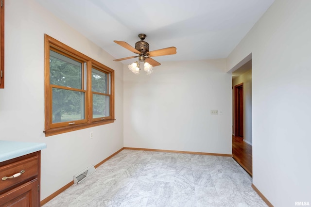 empty room with baseboards, visible vents, a ceiling fan, and light colored carpet