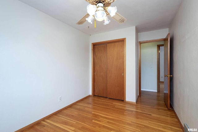 unfurnished bedroom featuring a ceiling fan, a closet, light wood-style flooring, and baseboards