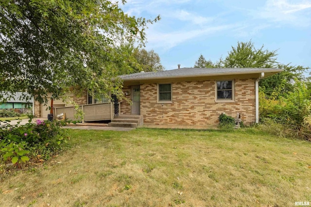 view of front of property featuring brick siding, a wooden deck, and a front yard