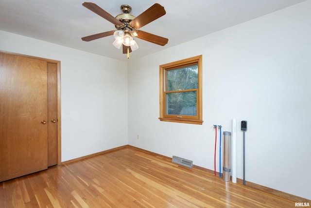 unfurnished bedroom with a ceiling fan, visible vents, baseboards, and wood finished floors