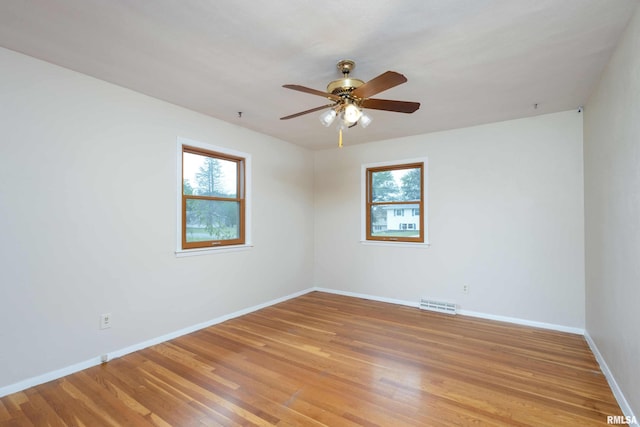 spare room featuring ceiling fan, wood finished floors, visible vents, and baseboards