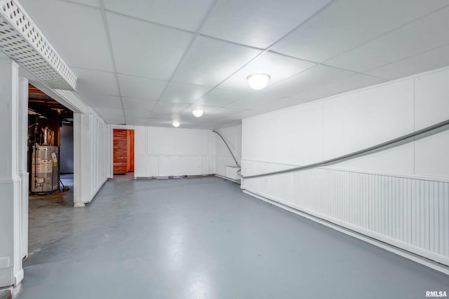 finished basement with gas water heater and a paneled ceiling