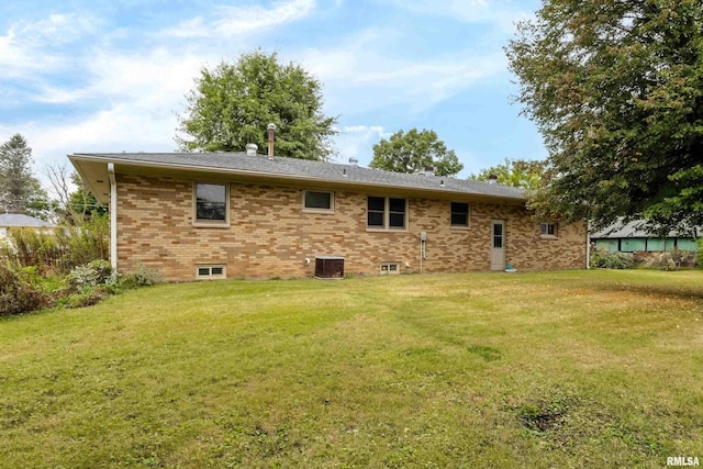 back of house with brick siding, a lawn, and central air condition unit