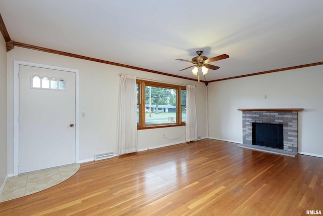 unfurnished living room featuring ceiling fan, wood finished floors, visible vents, a brick fireplace, and crown molding