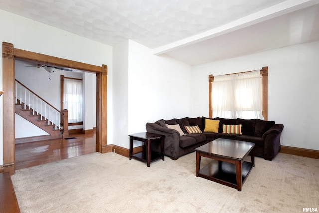 living room featuring beamed ceiling, ceiling fan, and light hardwood / wood-style flooring