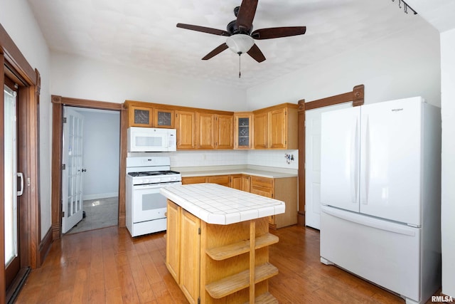 kitchen featuring tile counters, white appliances, decorative backsplash, a kitchen island, and light wood-type flooring