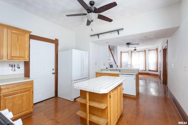 kitchen featuring white appliances, light wood-type flooring, tasteful backsplash, tile counters, and a kitchen island