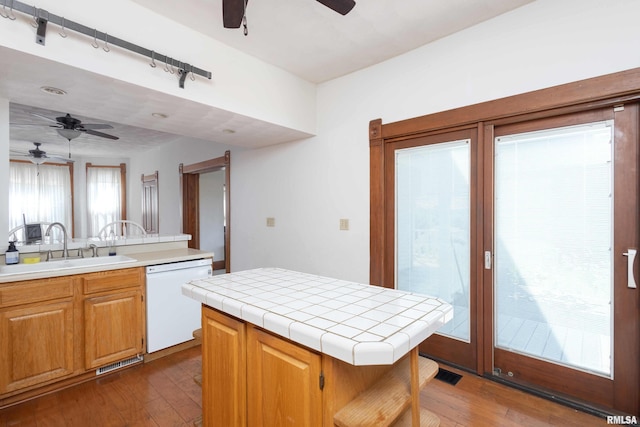 kitchen with white dishwasher, a center island, dark wood-type flooring, and tile countertops