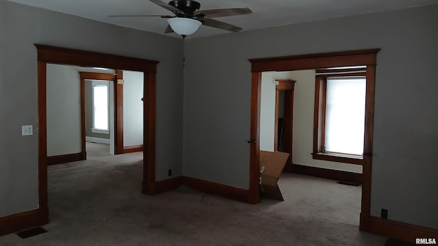 carpeted spare room featuring a wealth of natural light and ceiling fan