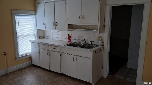 kitchen with decorative backsplash, white cabinetry, and sink