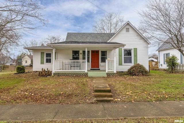 bungalow featuring covered porch and a front yard