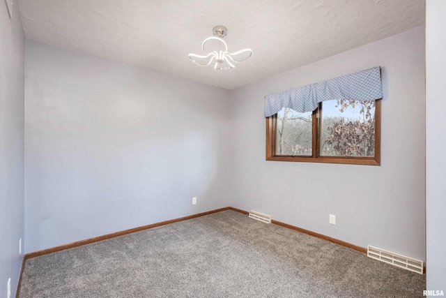 unfurnished room with carpet flooring, a textured ceiling, and a chandelier