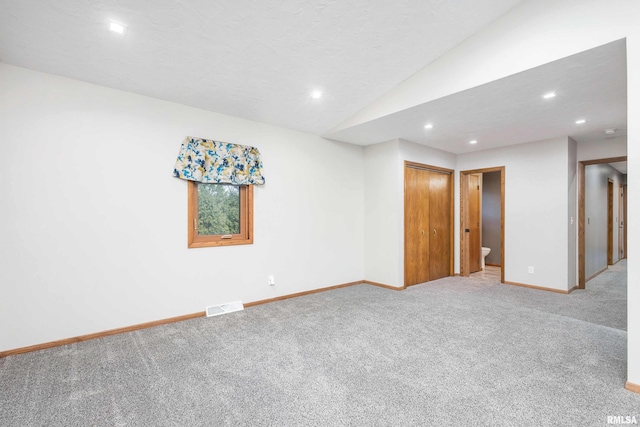 empty room with carpet floors and vaulted ceiling