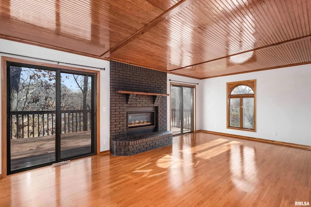 unfurnished living room with a brick fireplace, wood ceiling, and light wood-type flooring