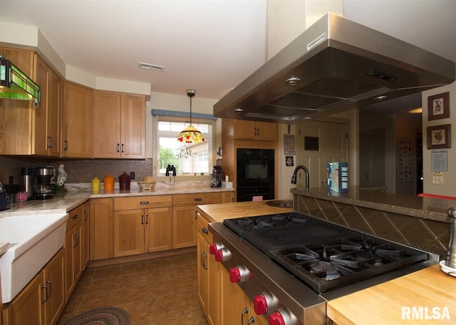 kitchen featuring hanging light fixtures, decorative backsplash, gas stovetop, double oven, and island exhaust hood