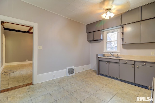 kitchen with gray cabinets, sink, and light tile patterned floors