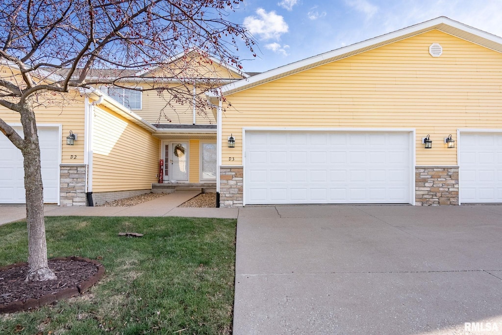 view of front of property featuring a garage, a front yard, stone siding, and driveway