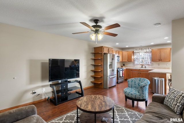 living room featuring a textured ceiling, ceiling fan, sink, and dark wood-type flooring