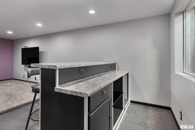 kitchen featuring kitchen peninsula, a breakfast bar, and light colored carpet