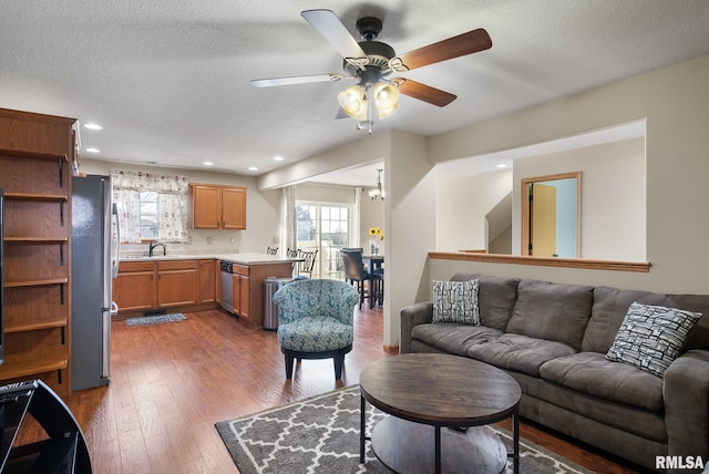 living room featuring a textured ceiling, dark hardwood / wood-style floors, ceiling fan, and sink