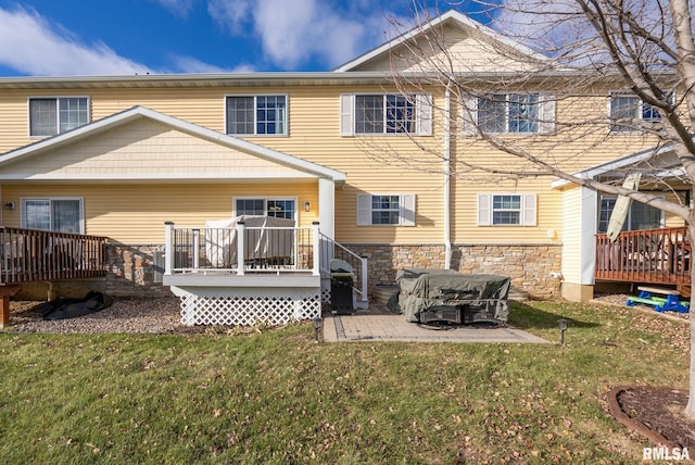 back of property with a lawn, a patio area, and a wooden deck