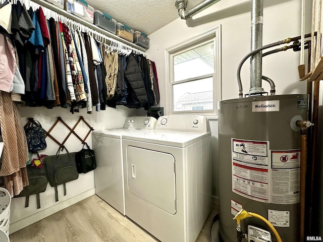 laundry room featuring washer and dryer, light wood-type flooring, a textured ceiling, and water heater