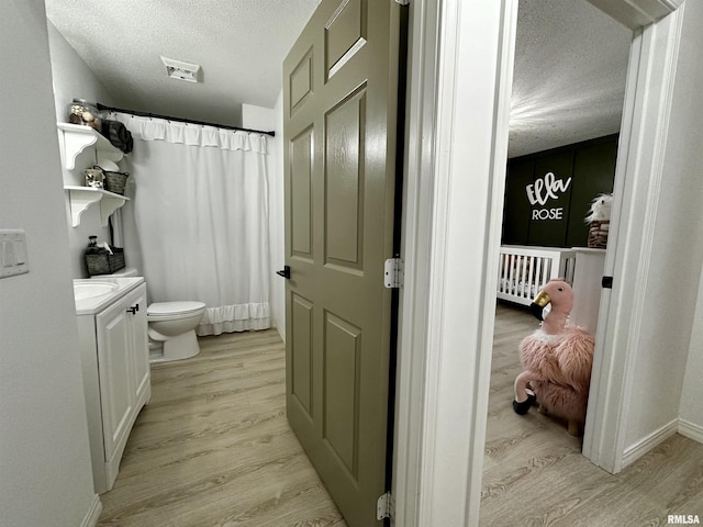 bathroom with wood-type flooring, vanity, a textured ceiling, and toilet