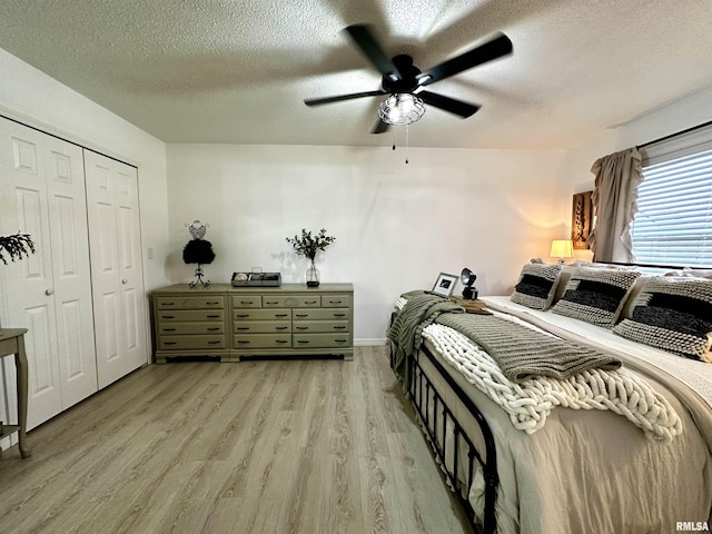 bedroom with ceiling fan, a closet, a textured ceiling, and light wood-type flooring