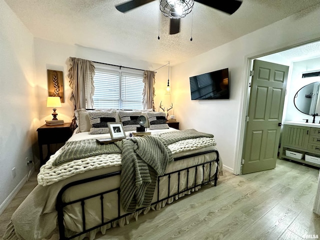 bedroom with a textured ceiling, ceiling fan, light wood-type flooring, and ensuite bathroom