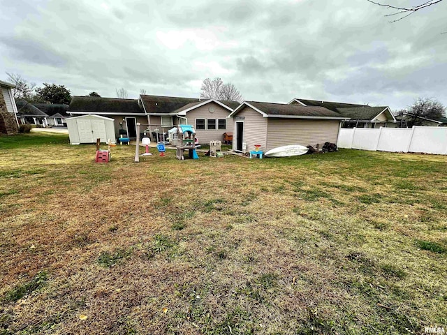 rear view of property with a yard and a storage unit