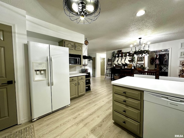 kitchen with ceiling fan with notable chandelier, light hardwood / wood-style floors, white appliances, and a textured ceiling