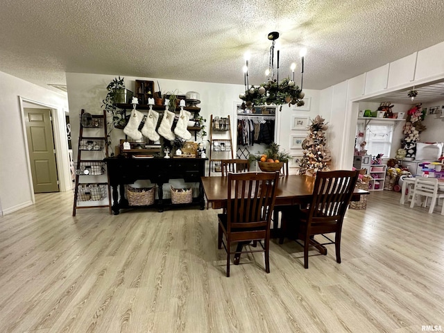 dining room with an inviting chandelier, a textured ceiling, and light hardwood / wood-style flooring