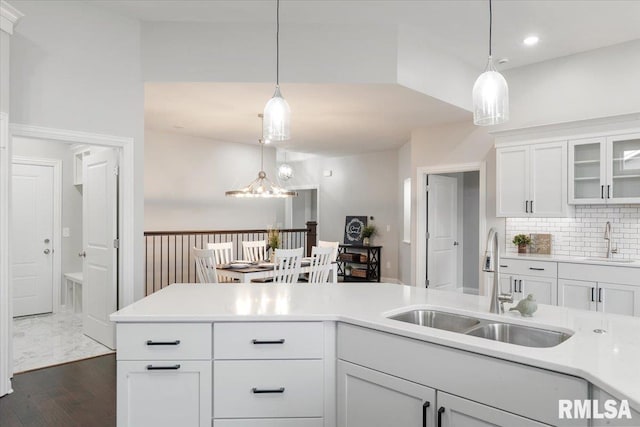 kitchen with pendant lighting, dark hardwood / wood-style flooring, white cabinetry, and sink