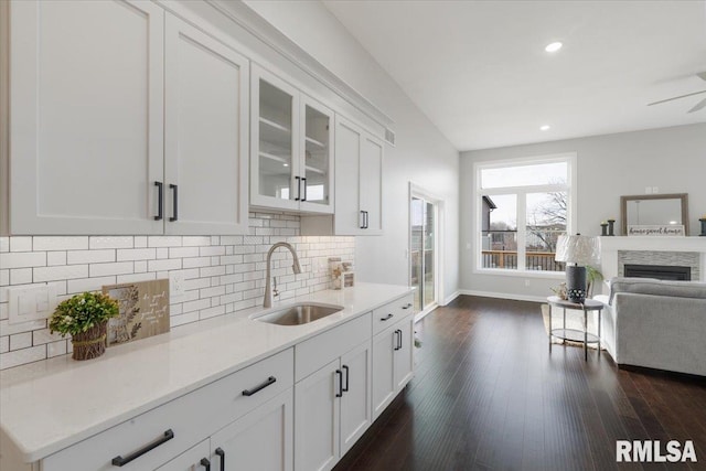 kitchen with white cabinetry, sink, light stone counters, dark hardwood / wood-style floors, and backsplash