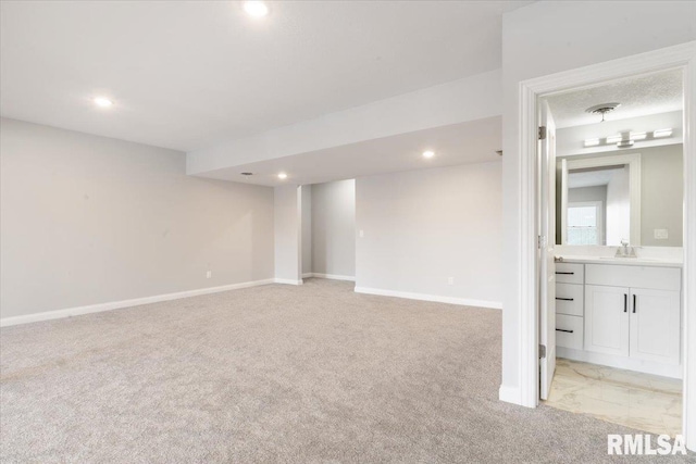 basement featuring sink and light colored carpet