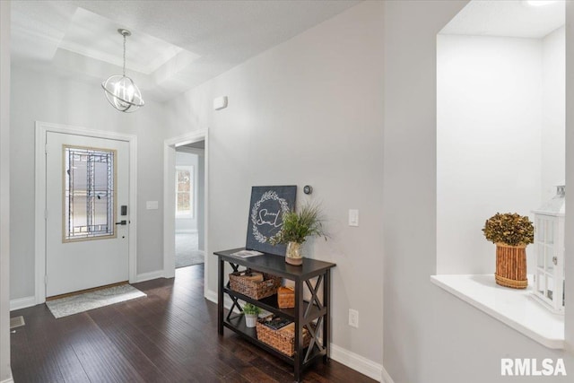 entryway featuring a notable chandelier, dark wood-type flooring, and a tray ceiling